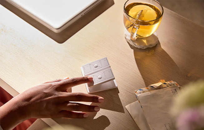 Pico Remote placed beside tea and papers demonstrating total lighting and shade control.