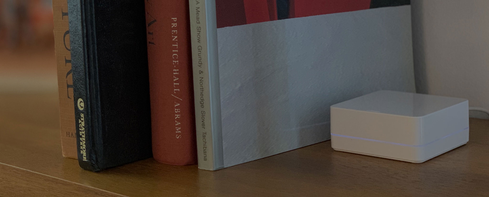 Smart home switch placed next to four books on a shelf